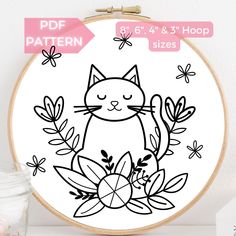 a black and white drawing of a cat sitting on top of some flowers in front of a wooden hoop