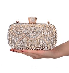 Radiant and sophisticated. Make an unforgettable entrance with the Opulent Floral Rhinestone Evening Clutch Bag, a dazzling accessory designed to enhance your evening attire with unparalleled glamour and elegance. Why We Love It...This stunning crystal clutch features an opulent floral design adorned with golden details and shimmering rhinestones, creating a vintage feel that's both glamorous and sophisticated. The rich composition of large white crystals and rhinestones on a gold backdrop ensures you'll shine brightly at any event. Perfect for celebrations, weddings, and parties, this rhinestone purse is available in Gold, Silver, and Black, allowing you to choose the style that best complements your outfit. The hasp closure, covered in rhinestones, adds an extra touch of luxury, while th Luxury Evening Wallets With Chain Detail, Wedding Clutch Purse, Crystal Purse, Beaded Clutch Bag, Pearl Clutch, Party Handbags, What Do, Wedding Clutch, Bridal Clutch