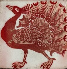 a red and white tile with a peacock on it