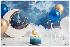 a blue and white cake with gold stars on it sitting in front of some balloons