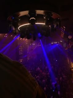 a crowd of people in a dark room with blue and purple lights on the ceiling