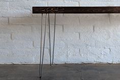 a wooden table with hair pins on it against a white brick wall and concrete floor