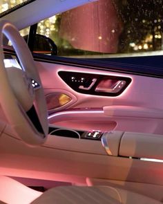 the interior of a car with its lights on and steering wheel illuminated by pink light