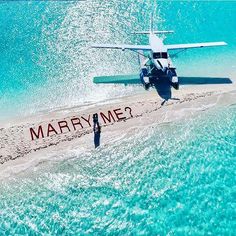 an airplane is flying over the water with a message written on it that says marry me?