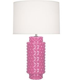 a pink table lamp with a white shade on the base and a light in front of it