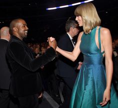 a woman in a blue dress is shaking hands with a man in a black suit