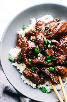 meat and rice on a plate with chopsticks in the middle, ready to be eaten