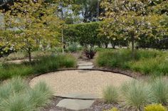 a circular garden area with gravel, grass and trees