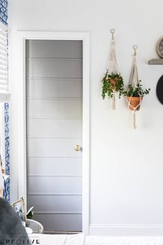 there is a clock hanging on the wall next to a door and potted plants