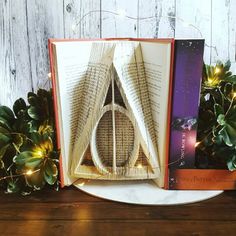 an open book sitting on top of a wooden table next to christmas lights and greenery