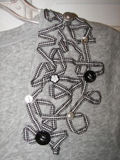 a gray sweater with black and white buttons on it