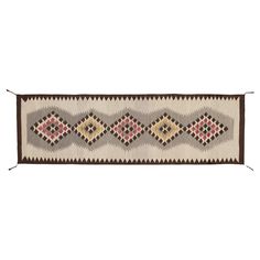 a long rug with geometric designs on the sides and brown trimmings, in various colors