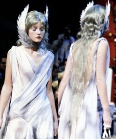 two women in white dresses with long hair and angel wings on their heads walking down the runway