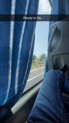 someone's feet hanging out the window of a vehicle with blue curtains on it