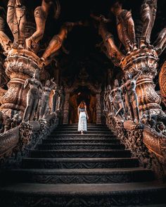 a woman is standing on the stairs in front of an intricately carved building with statues