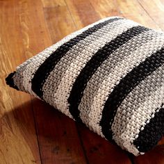 a black and white striped pillow sitting on top of a wooden floor