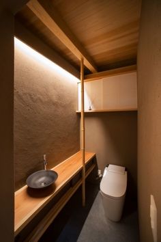 a bathroom with a toilet, sink and wooden shelves in it's corner area