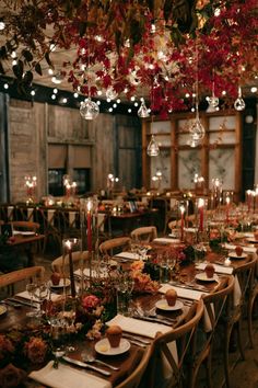 a long table set up with candles and flowers in the center for a wedding reception