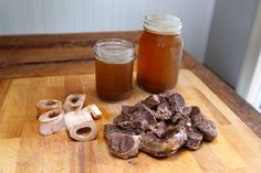 two jars filled with liquid sitting on top of a wooden cutting board next to mushrooms