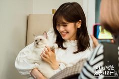 a woman holding a white cat in her arms