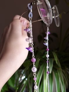 Introducing a glasses chain inspired by the enchanting wisteria flowers. This delicate piece features intricate flower beads, complemented by soothing lepidolite beads and imitation pearls. Designed to add a touch of femininity to your eyewear, this chain is as elegant as it is functional. Elevate your accessory game with this enchanting wisteria-inspired glasses chain. This eyeglass chain might be slightly heavier than regular chains because of some stone beads and crystals. Actual colors of an Purple Fairycore Jewelry For Party, Handmade Bohemian Glasses Chains For Party, Bohemian Handmade Glasses Chains For Party, Bohemian Purple Glass Necklace, Handmade Elegant Glasses Chains For Festivals, Elegant Handmade Glasses Chains For Festivals, Whimsical Purple Beaded Jewelry, Elegant Handmade Festival Glasses Chains, Purple Glass Beads For Jewelry Crafting