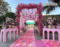 an outdoor ceremony with pink and white flowers on the aisle, surrounded by tall planters