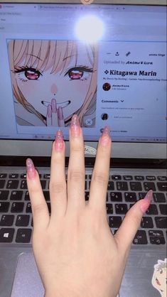 a woman's hand on top of a laptop keyboard with an anime character drawn on the screen