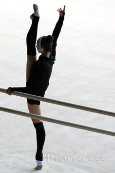 a woman in black is performing on the ice rink while wearing headphones and holding her arms up