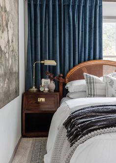 a bedroom with blue drapes and white bedding in front of a painting on the wall