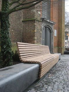 a wooden bench sitting on top of a cobblestone street next to a tall brick building