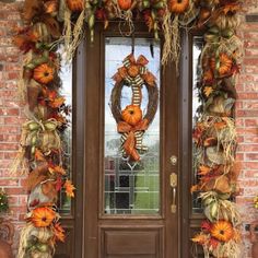 a front door decorated for fall with pumpkins and hay wreaths on the side