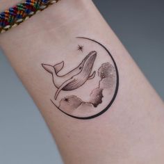 a small tattoo on the wrist of a woman with a whale in it's mouth