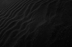 black sand dunes in the desert with small white dots on it's top and bottom