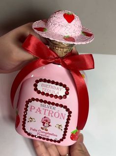 a hand holding a pink bottle with a red ribbon around it that says happy birthday silver patron