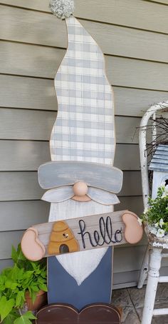 a wooden sign sitting on top of a chair next to a planter filled with flowers