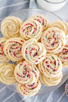 white frosted cookies with sprinkles on a glass plate