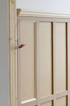 an empty room with white walls and wooden paneling on the wall, along with a red door handle