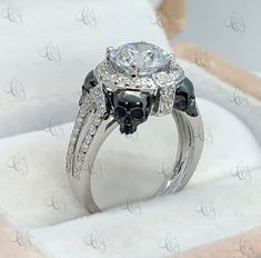 an engagement ring with black and white diamonds on the side, in a gift box