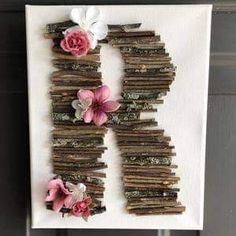 the letter h is made out of sticks with flowers on them and hung on a wall