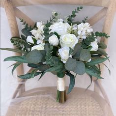 a bouquet of white flowers sitting on top of a wooden chair