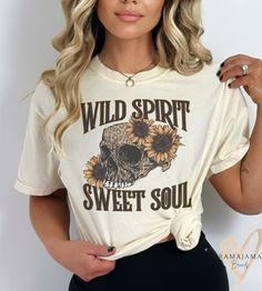 "This stunning white t-shirt is perfect for anyone who embraces their wild side while also cherishing their sweet soul. The striking skull graphic, featuring intricate detailing and bold lines, adds a touch of edge and intrigue to this classic wardrobe staple. The phrase \"Wild Spirit Sweet Soul\" is emblazoned across the front in eye-catching typography, making a powerful statement about your free-spirited nature and your kind heart." Cheetah Skull, Personalized Gift Baskets, Hip Tattoos, Hip Tattoos Women, Skull Png, Tattoos Women, Skull Graphic, Wild Spirit, Classic Wardrobe Staples