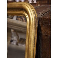 a gold framed mirror sitting on top of a wooden table