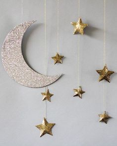 the moon and stars are hanging from the string on the wall, which is decorated with gold glitter