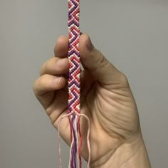 a hand holding up a string with pink and purple beads on it's end