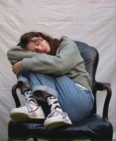 a woman is sitting in a chair with her head on her hands and eyes closed