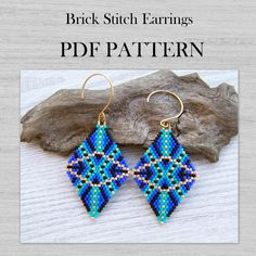 a pair of blue and green beaded earrings sitting on top of a piece of wood