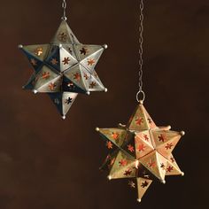 two christmas ornaments hanging from chains on a brown background, one has an ornament in the shape of a star