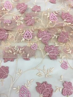 pink and white floral embroidered mesh fabric with flowers on it's side, close up