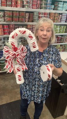 a woman holding up a candy cane wreath