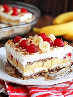 a piece of cake on a plate with bananas and raspberries